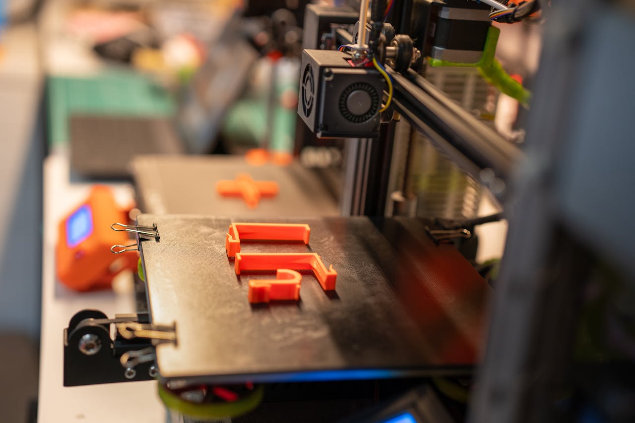 services-02 Detailed view of a 3D printer creating an orange plastic part showcasing advanced technology.