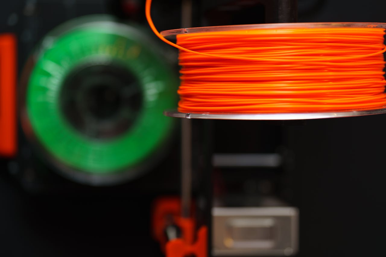gallery-04 Detailed view of orange and green 3D printer filament spools, perfect for creative and industrial projects.