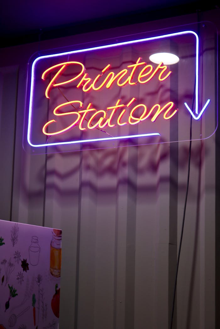gallery-02 Vibrant neon 'Printer Station' sign illuminating indoors at night with a modern feel.