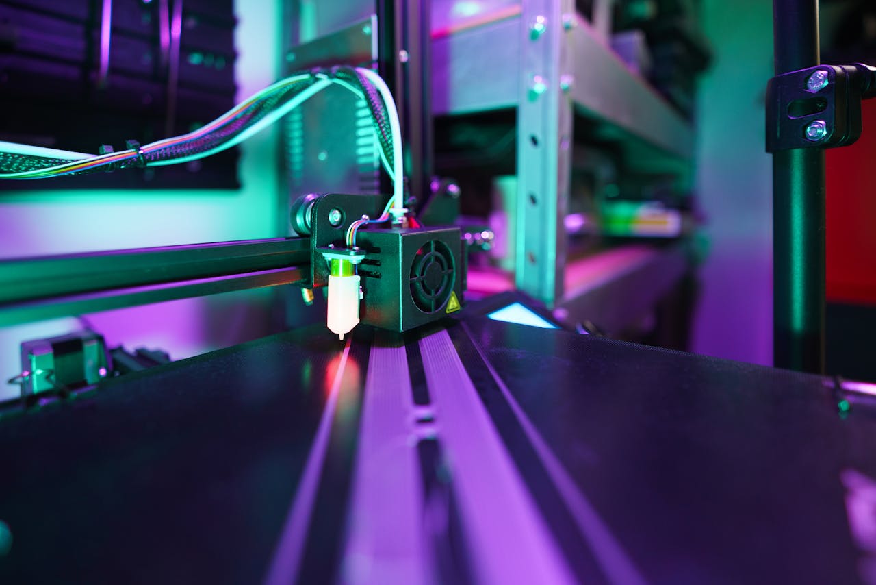 portfolio-02 A detailed view of a 3D printer in operation with vibrant neon lighting creating a futuristic tech ambiance.